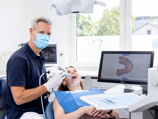 Zahnarzt Dr. Schlotthauer erstellt mit dem PrimeScan Intraoralscanner einen digitalen Zahnabdruck einer Patientin.